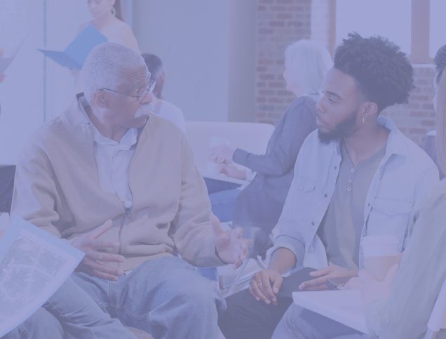 Young man in white coat talks to older man
