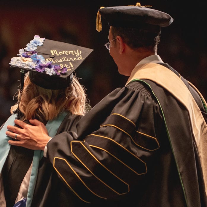 student in cap and gown at graduation with university president