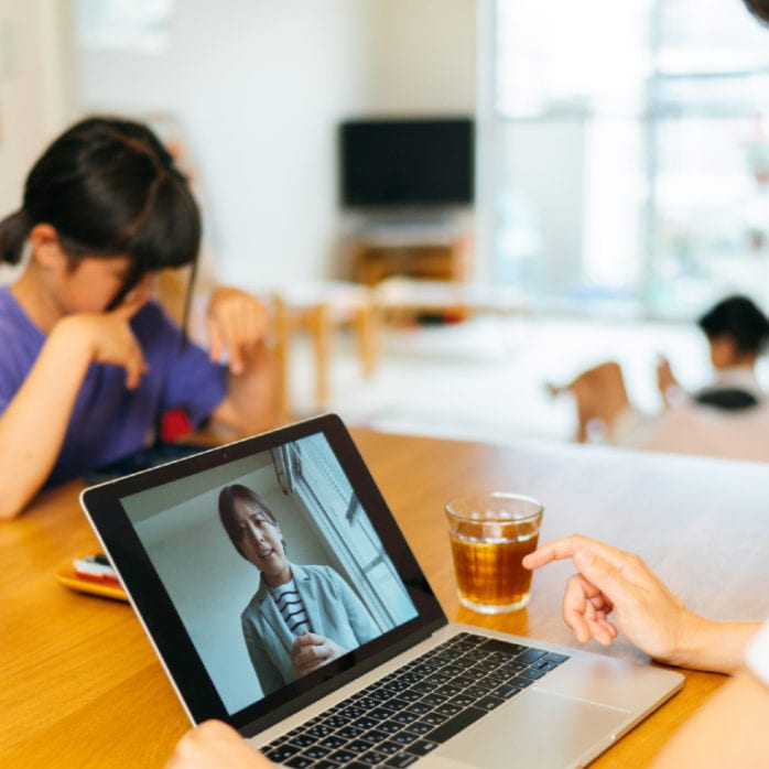 mother utilizing telehealth with child in background